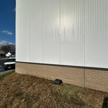 The same white metal panel wall with the graffiti removed and the finish left intact
