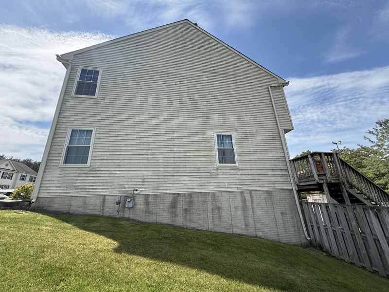 Cream vinyl siding on a Frederick, MD house darkened with algae streaks and dirt before soft washing