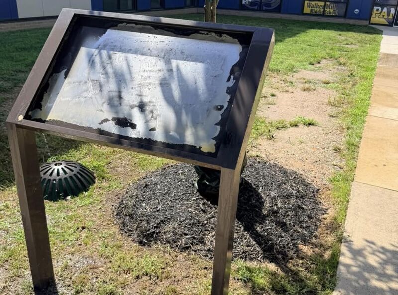 The same school sign panel after graffiti removal, readable again with some shadow staining remaining around the edges